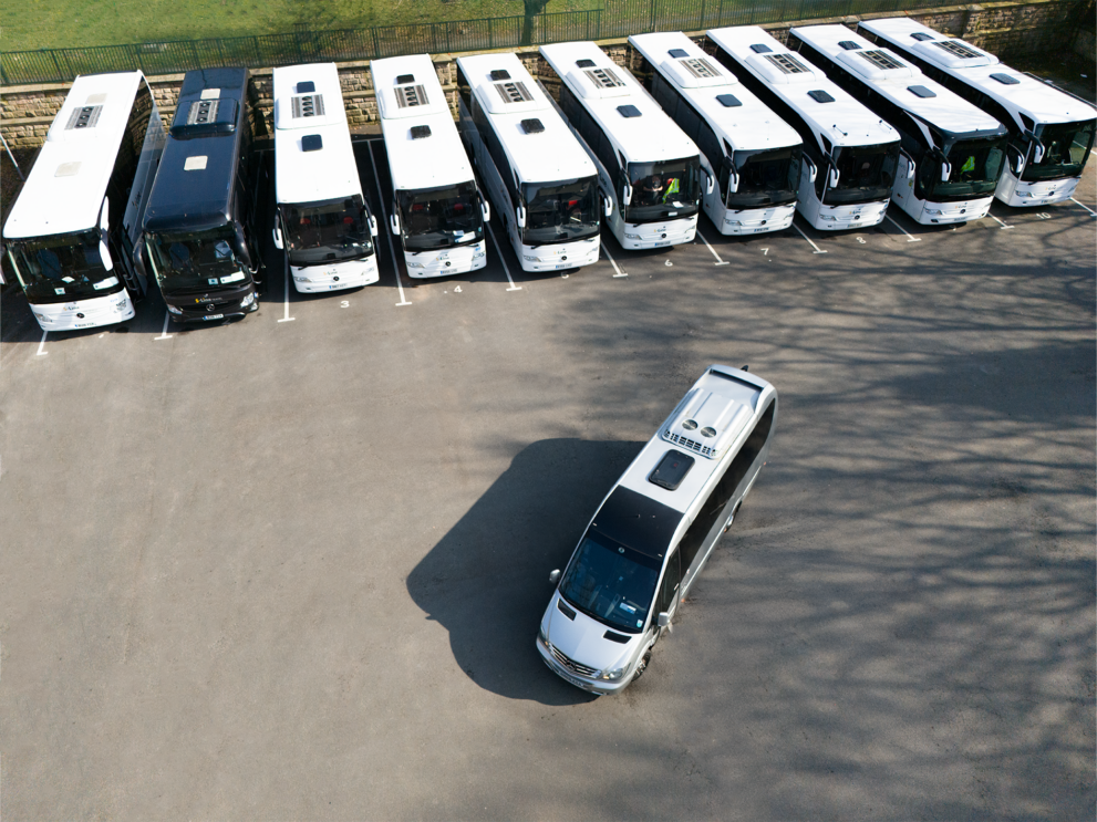 Aerial DJI drone photograph of S-Line Travel coach hire fleet and accessible minibus parked in formation in the North West, showcasing modern school transport and UK group travel services.